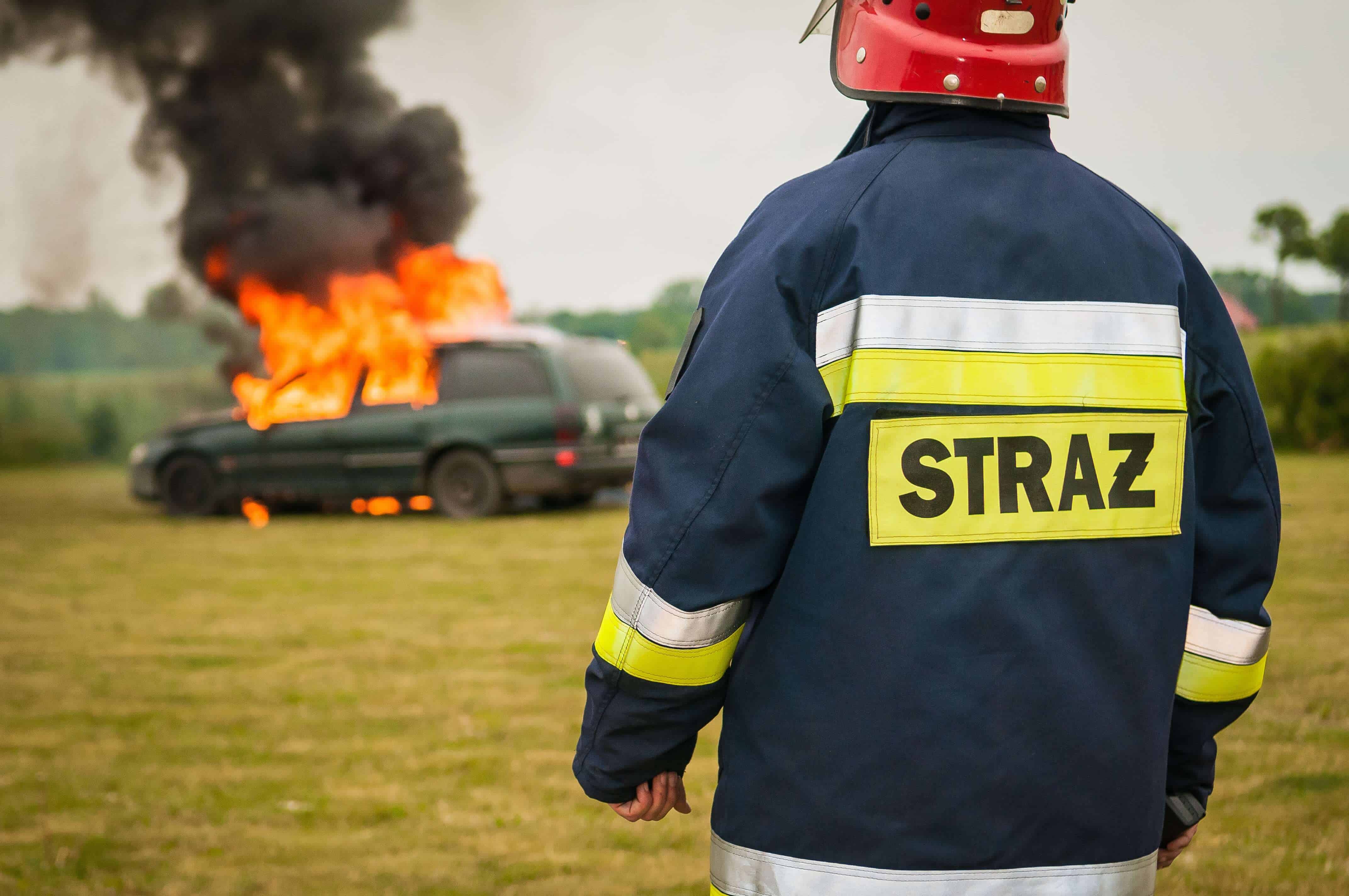 alt="Firefighter looking at the car that is burning.